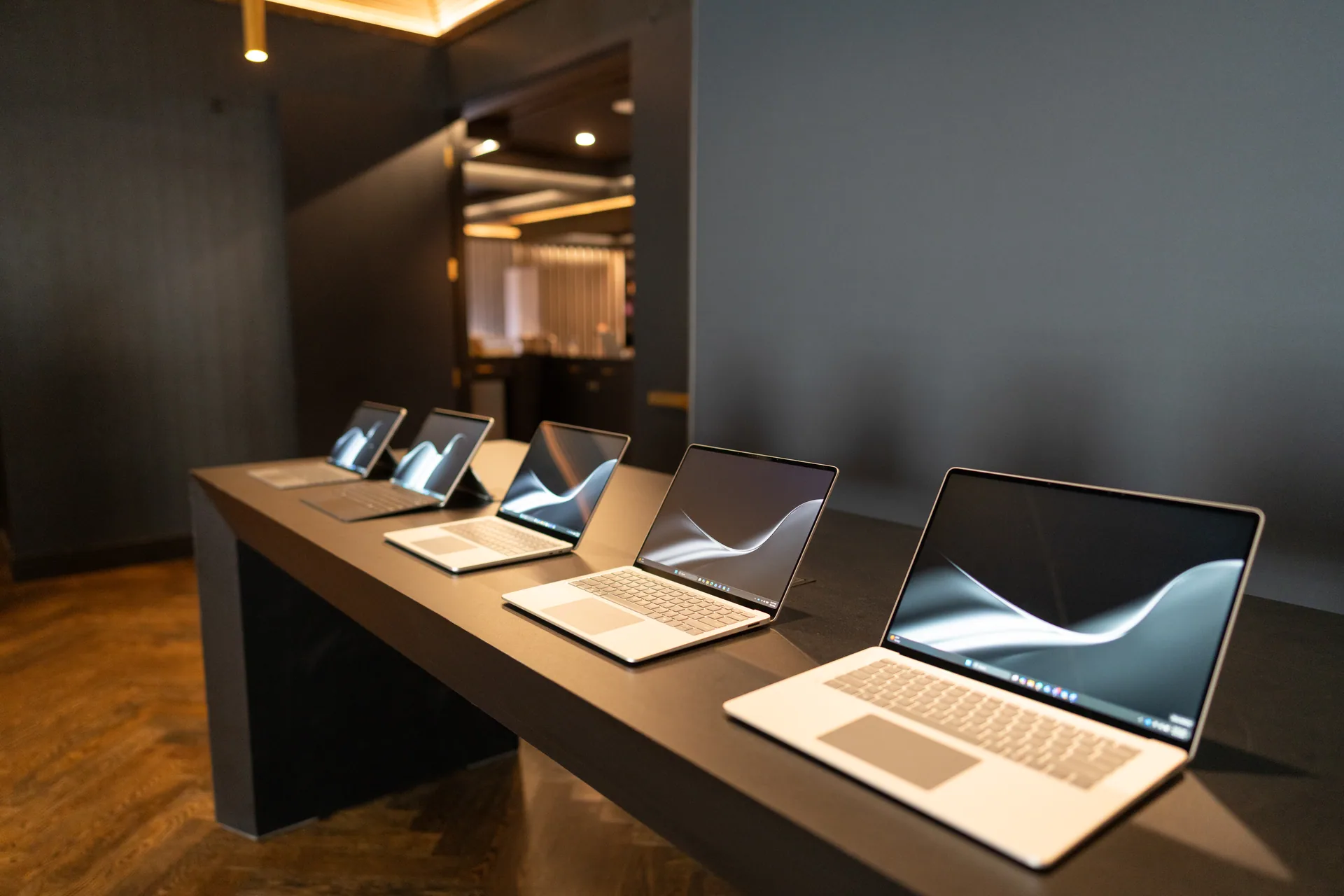 A Cadence 3 product environment: laptops staged along a dark table, lit doorway beyond.